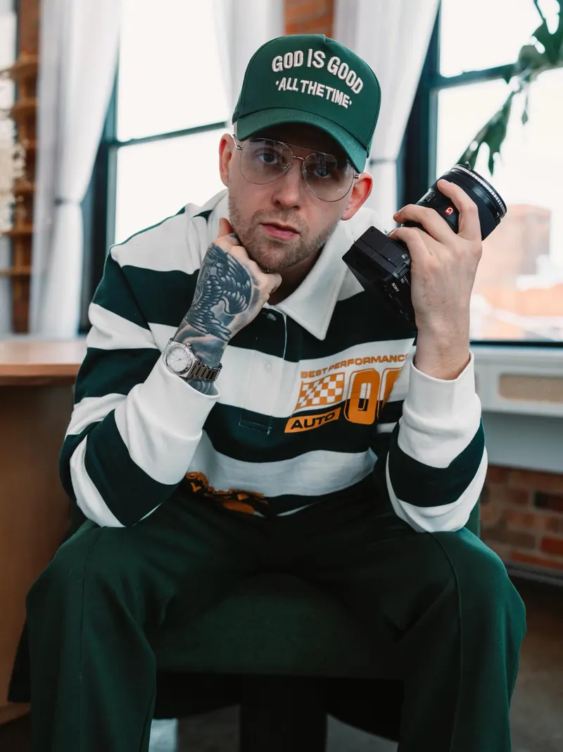 Chris Dodd in a green cap and striped rugby shirt holding a Sony camera by a loft window